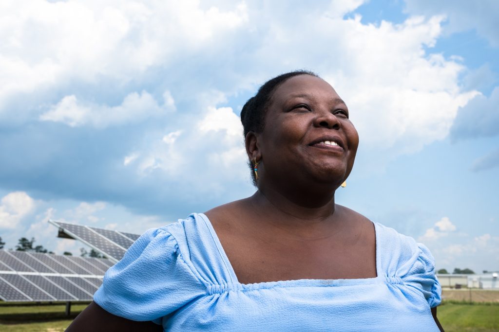 The image features a woman in front of solar panels, potentially related to the work of the Hive Fund for Climate and Gender Justice.